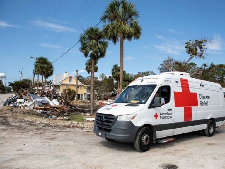 disaster relief vehicle in front of damage in neighborhood