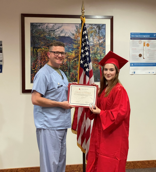 A person in a cap and gown holding a certificate