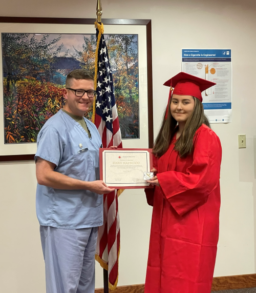 A person in a cap and gown holding a certificate