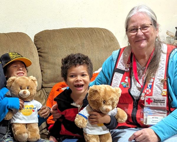 Red Cross volunteer Diana Sommer talks to Tihai Whittaker, 7, and Sermariana Whittaker, 5, whose home was destroyed by a fire. She gave each child a Build-A-Bear that provided comfort and support for the children who lost everything in the fire. (Red Cross photo by John Mathews)