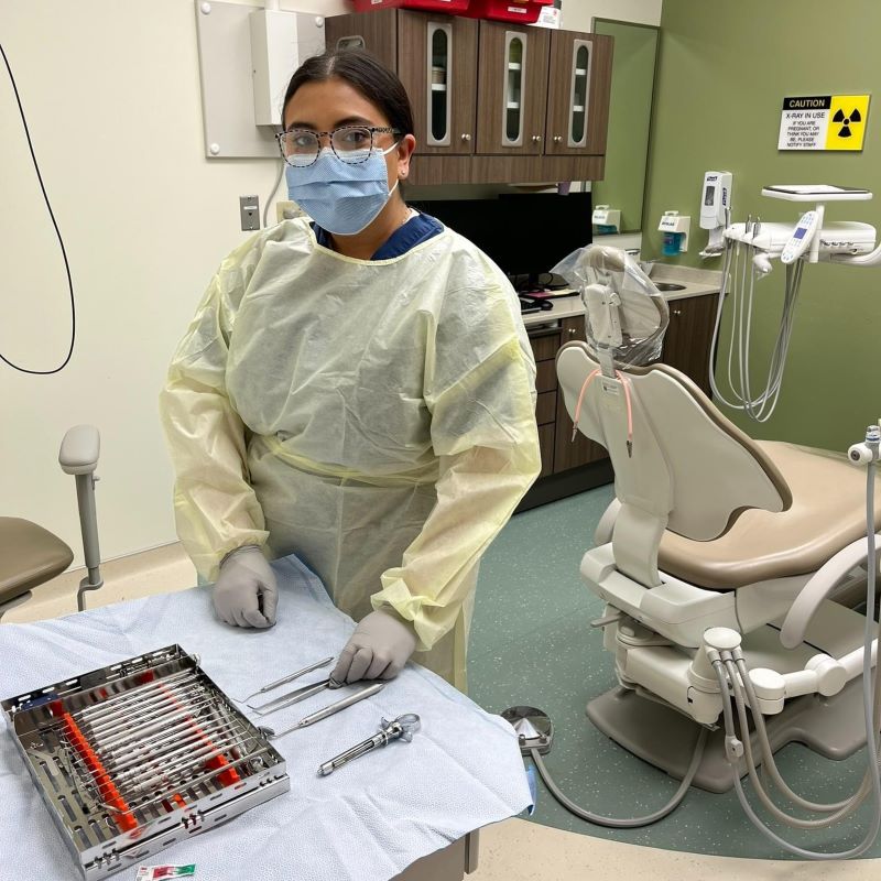 Ana Valeria Lopez, a recent graduate of the dental assistant training program at Fort Leonard Wood, Missouri, stands ready to assist a dentist with a patient. (Red Cross photo by Ann Vastmans)
