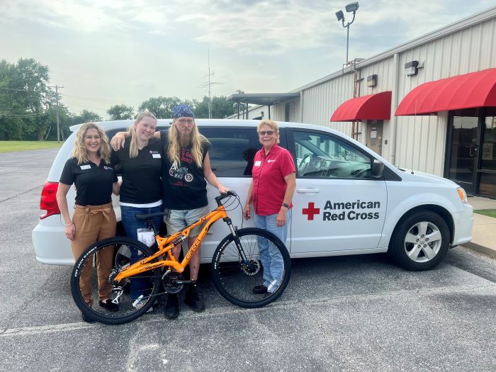 image of two red cross volunteers and a veteran with a newly gifted bike