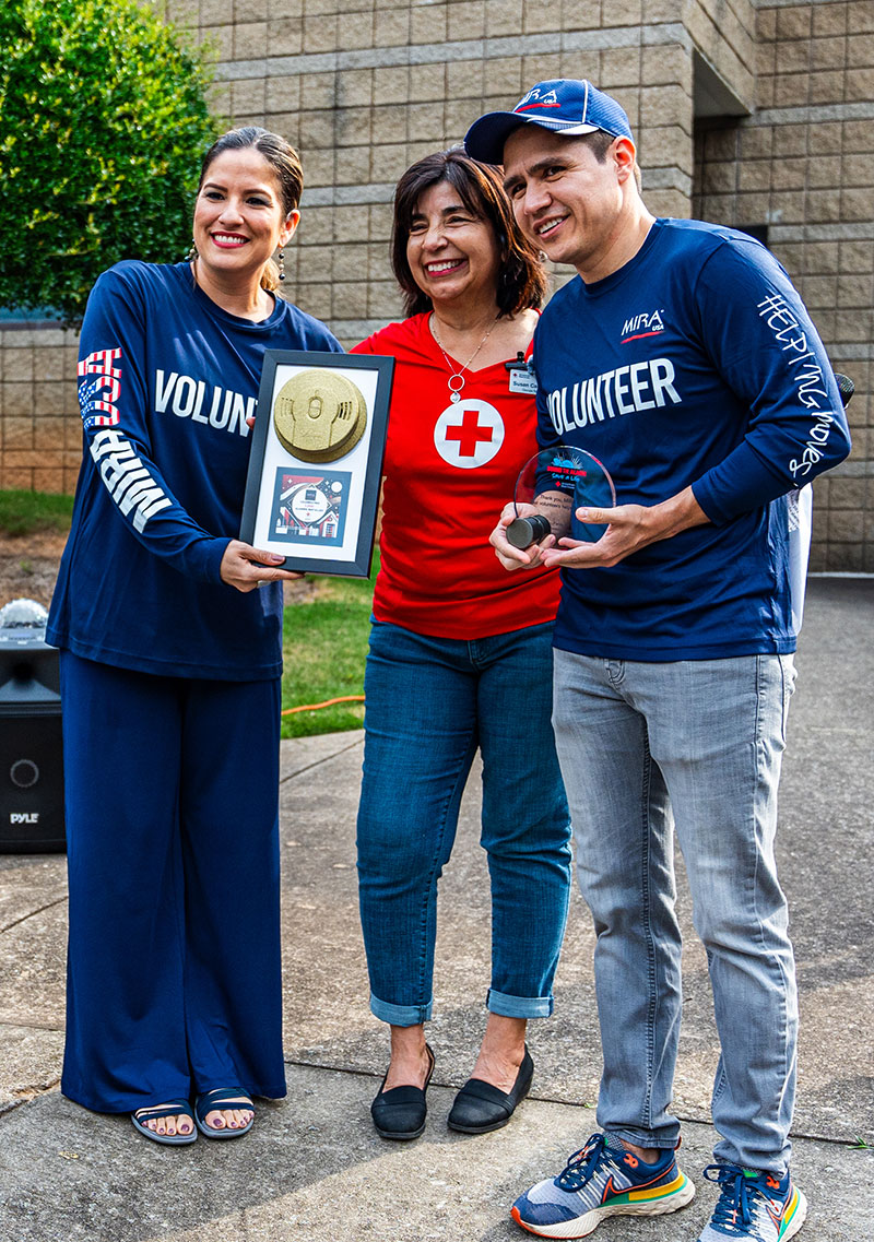 Three volunteers holding awards received from the Red Cross.
