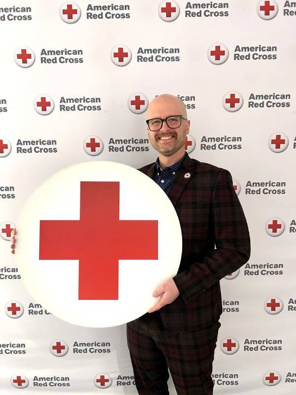 Man in suit holding Red Cross
