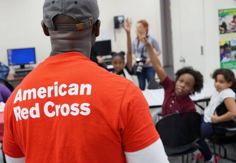 Red Cross instructor stands in front of children