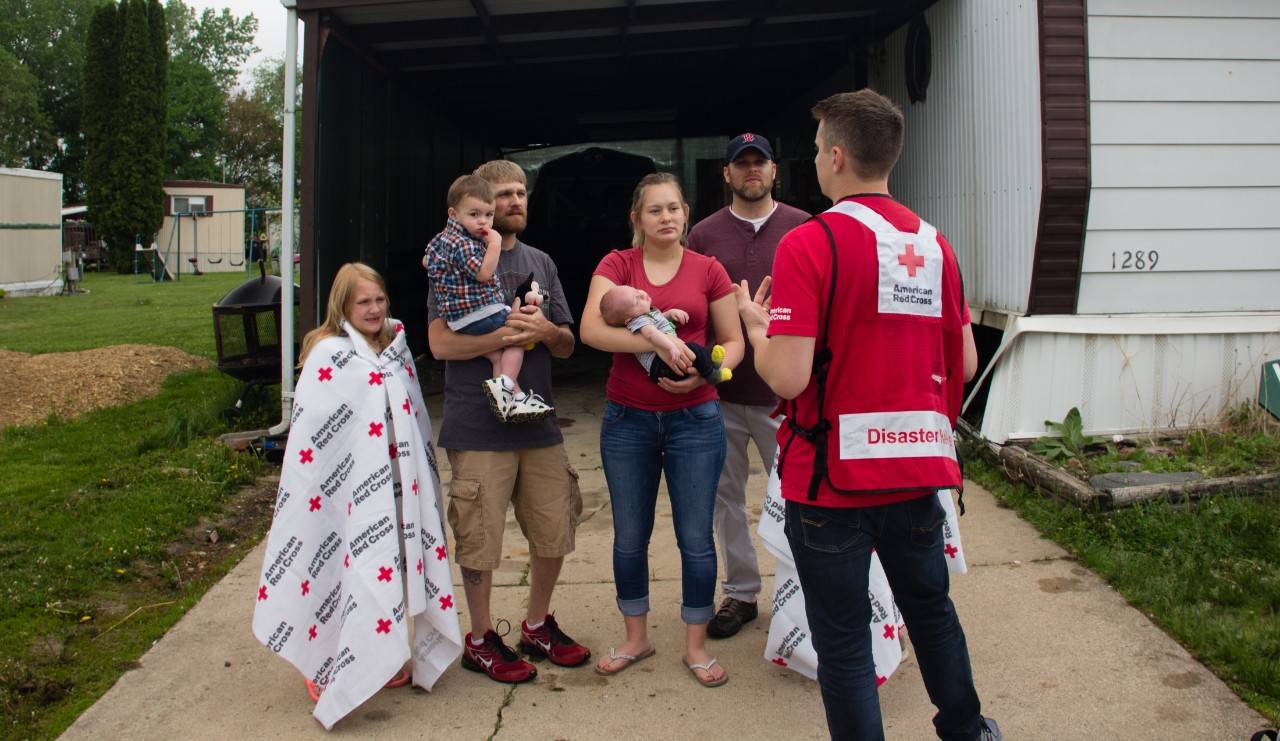 May 19, 2018.
Home Fire - Sound The Alarm
Dubuque, Iowa. 
Pictured: (Left to right back) Wyatt Avenarius, Brett Avenarius, Stephanie Elliott, Steve Avenarius
(Left to right front) Ivy Avenarius, Waylon Avenarius (2 months), and American Red Cross DAT member, Tyler Breitbach.

The Avenarius family of Dubuque, Iowa is alive today because smoke alarms alerted them to a late night fire behind the dryer in their home. Seven family members escaped thanks to the alarms whch had been installed by the American Red Cross just seventeen days before.

The alarms were installed as part of "Sound The Alarm," a national home fire prevention campaign. Red Cross volunteers install free smoke alarms in any home that needs them. Volunteers also provide fire prevention and safety information. In addition they will help residents develop a custom escape plan, showing the best ways to escape the home in the event of a fire.

Brett, Stephanie and Steve Avenarius, along with 3 young children, were in the house that night  when the smoke alarms sounded at 2am.  I always thought that if a fire ever went off in my house I would surely wake up," said Brett, "I mean it s smoke, who wouldn t wake up to that?" He answered his own question with a newfound respect for the lesser-known threats of fire, "When the smoke alarms went off and I opened my eyes, and saw that the smoke was that thick in the housescary. I mean we were that close to death. It s heartbreaking to think that a 1 year old, a 2-month old, an 8-year-old and a 10-year-old would never be able to breathe another day, or experience anything because their lives would have been cut short if we hadn t made that decision to accept Red Cross help and put the smoke alarms in. 

Brett will always remember the words from a Key West Firefighter that morning,  He said people don t die because of fires, they die because of the smoke. You wouldn t have woken up. The smoke wouldn t have woken you up. The fire alarms woke us up and if it wasn t for