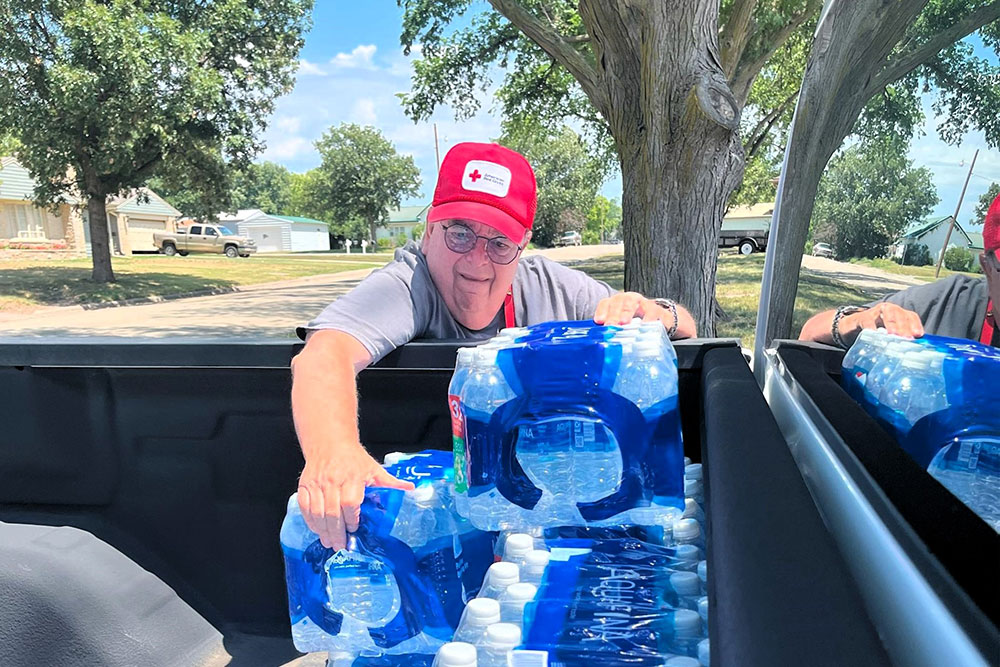 Red Cross volunteer Eric Kohn moves cases of water in the bed of a Red Cross pickup truck.