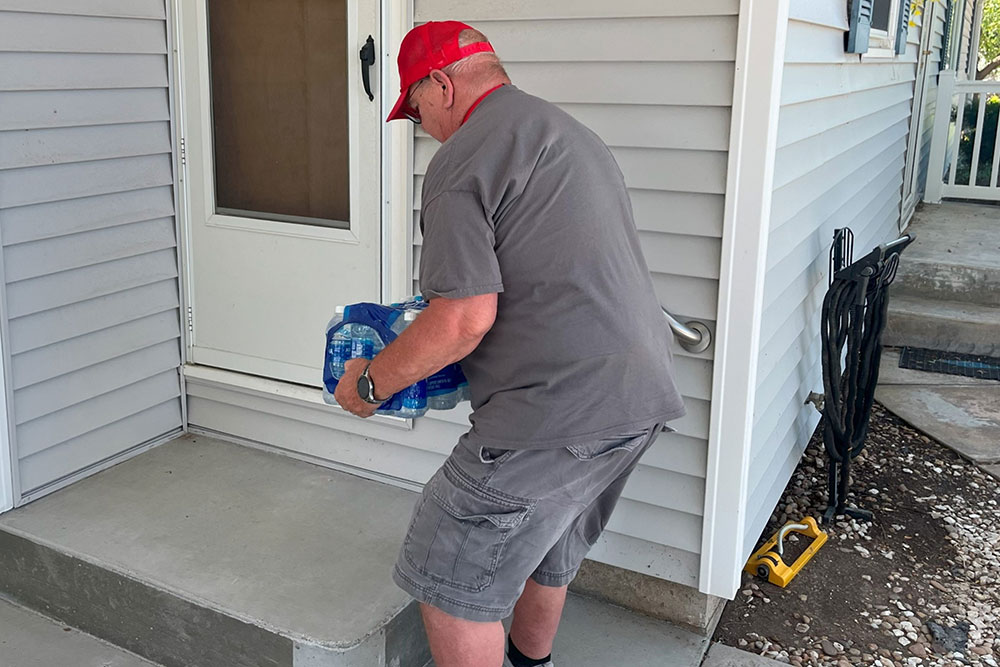 Red Cross volunteer Eric Kohn places a case of water at the door of a home.