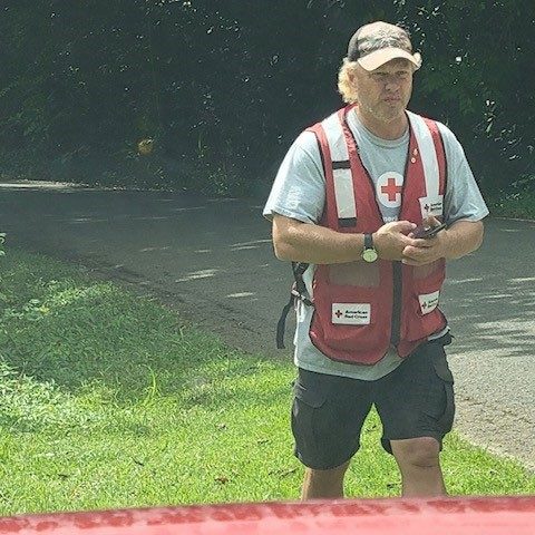 Pat O’Malley with Red Cross vest and holding phone.