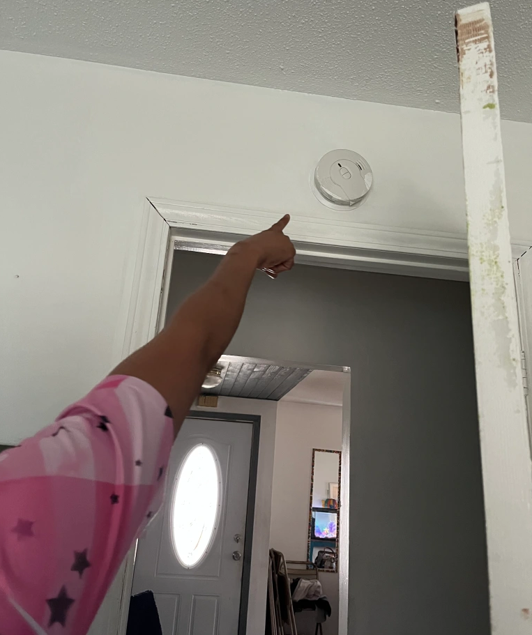 person pointing to a smoke alarm
