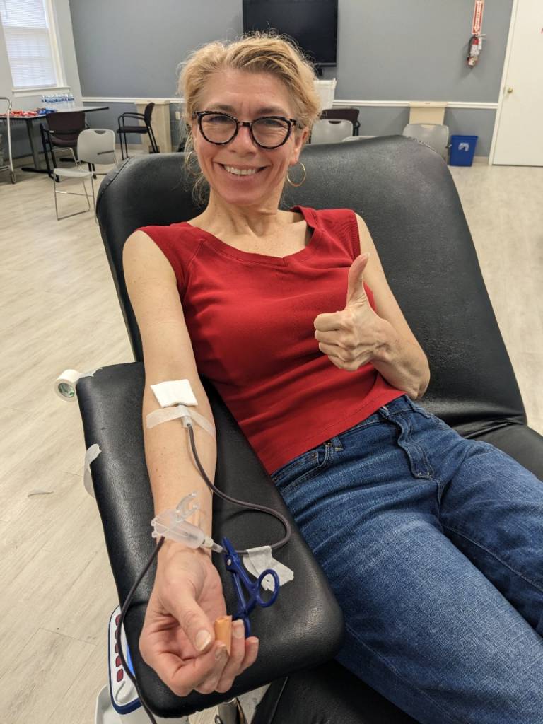 Photo of Alison Risso in a chair donating blood at a Red Cross blood drive
