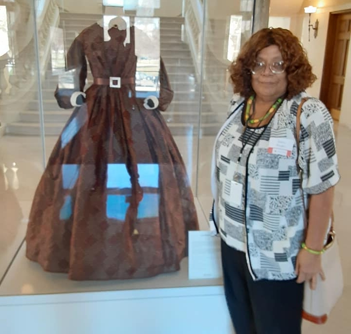 A person standing next to a dress