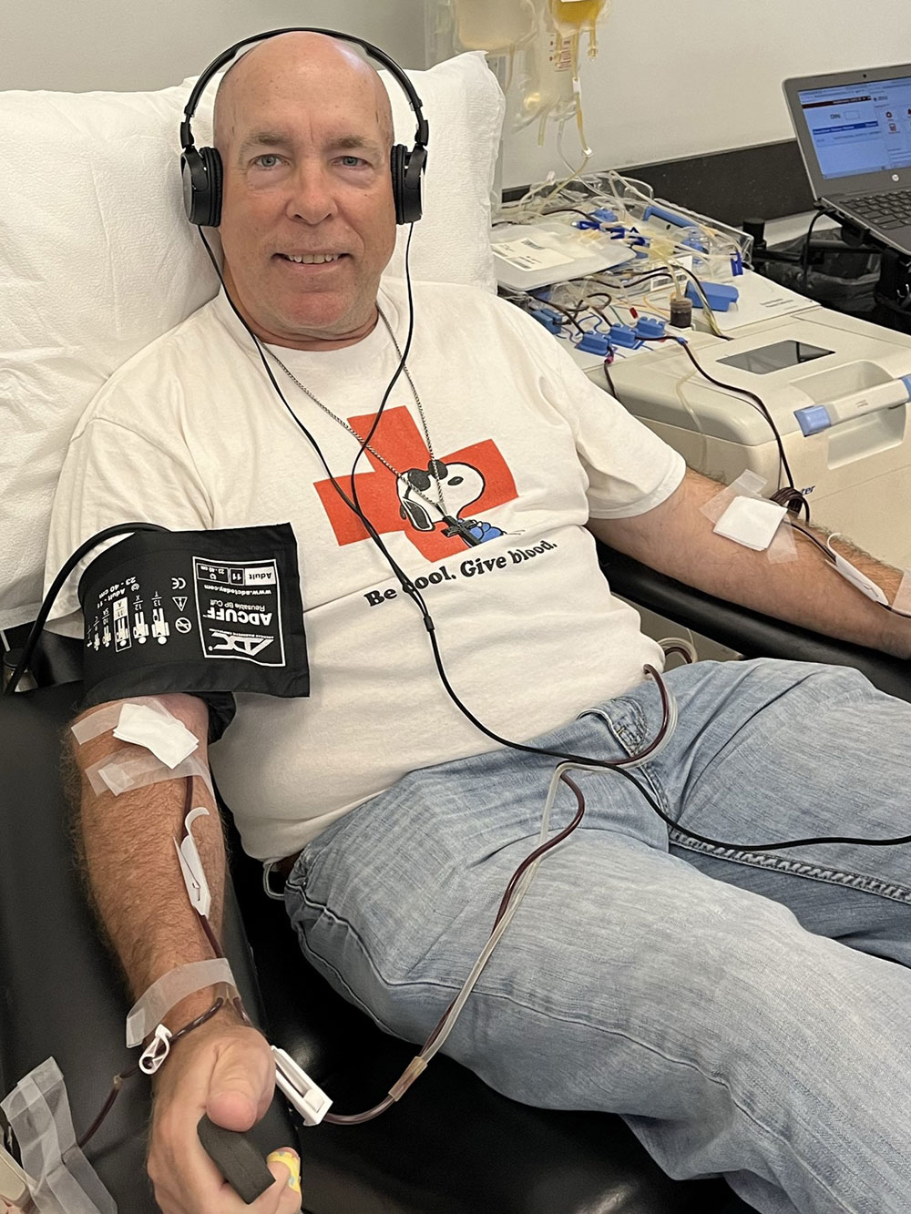 Scott Whittington wearing headphones sitting in cot donating blood