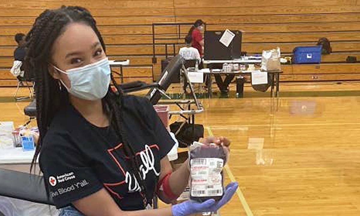 TCU student Winter Harris holding a unit of blood at a Red Cross blood drive. 
