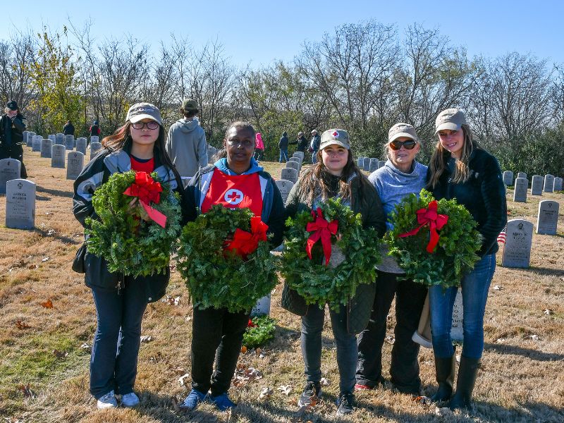 red crossers holding wreaths