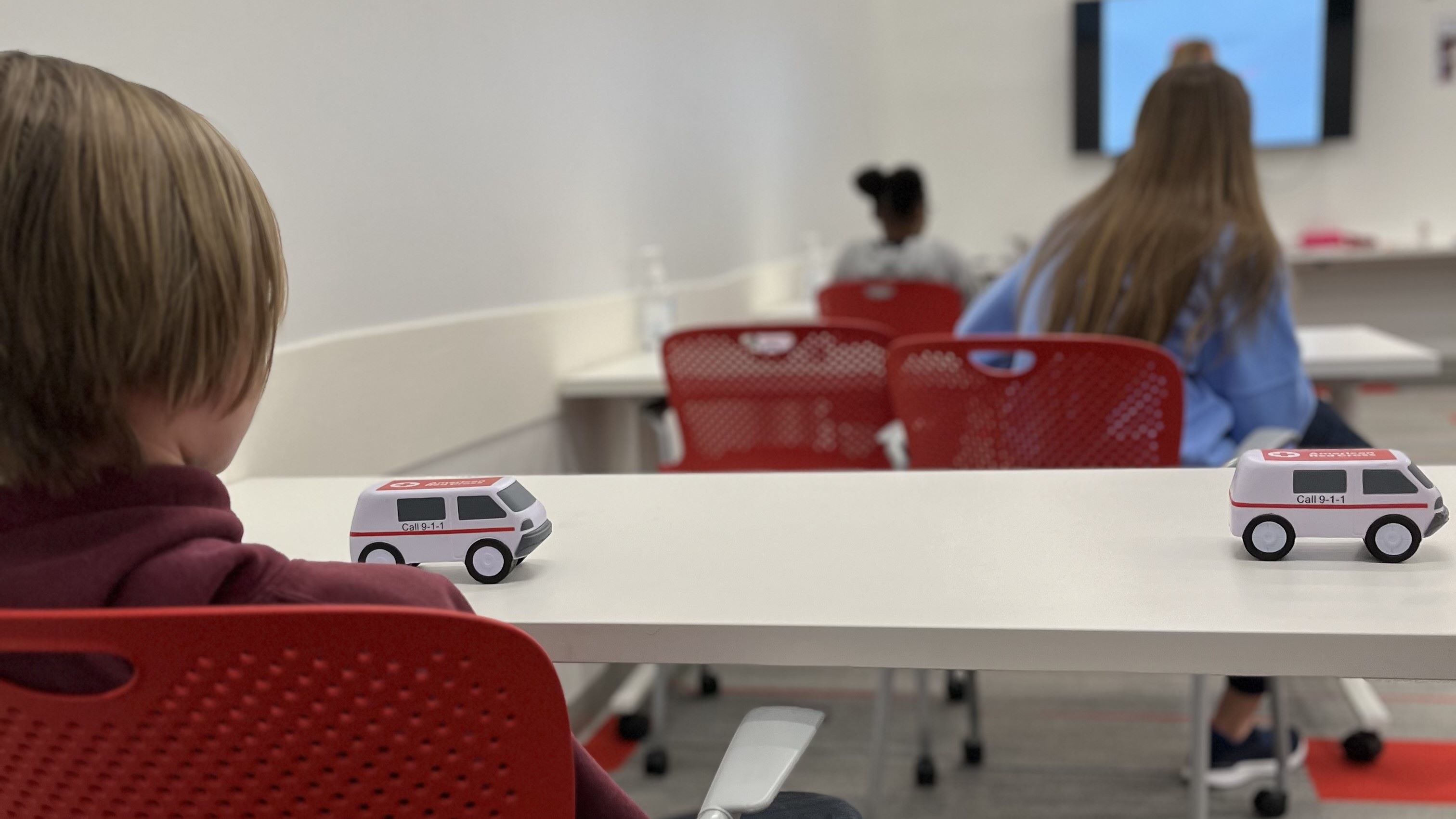male student sitting at table with toy truck