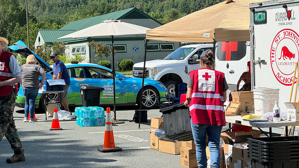 American Red Cross volunteers helping others in parking lot with canopies and supplies.