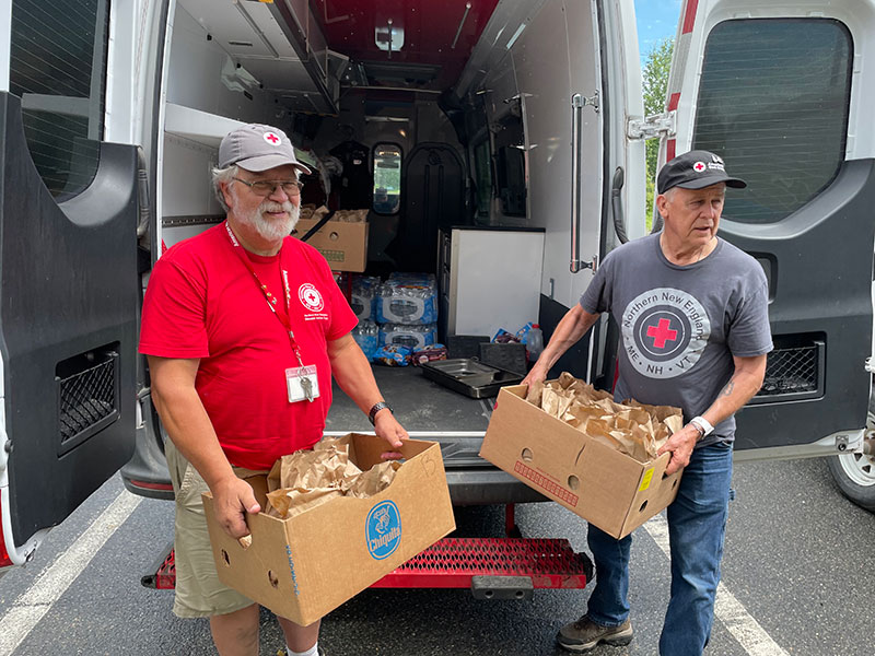 American Red Cross volunteers unloading supplies from the back of a van.