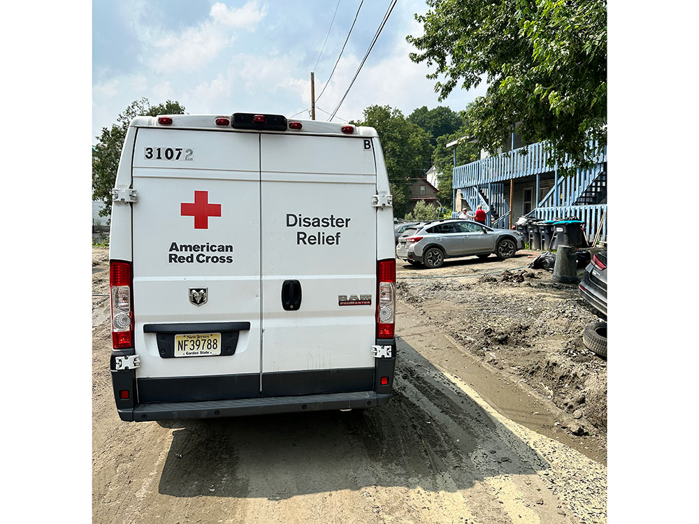 Back of Red Cross Disaster Relief van driving on a muddy road.