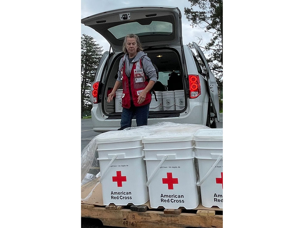Red Cross volunteer loading 5 gallon Red Cross buckets into the back of a van.
