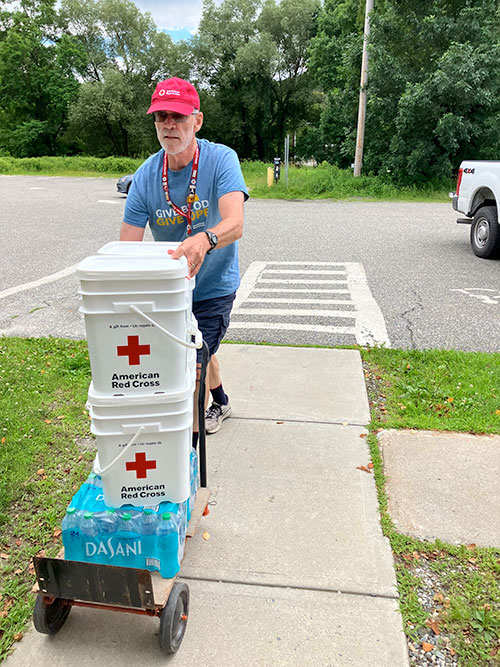 American Red Cross volunteer Pete Basiliere with bottled water and five gallon American Red Cross buckets on a hand cart.