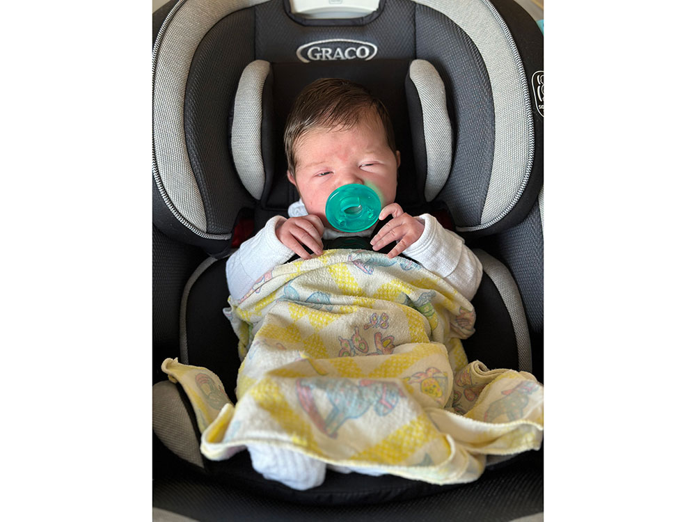 Baby in car seat with pacifier and blanket
