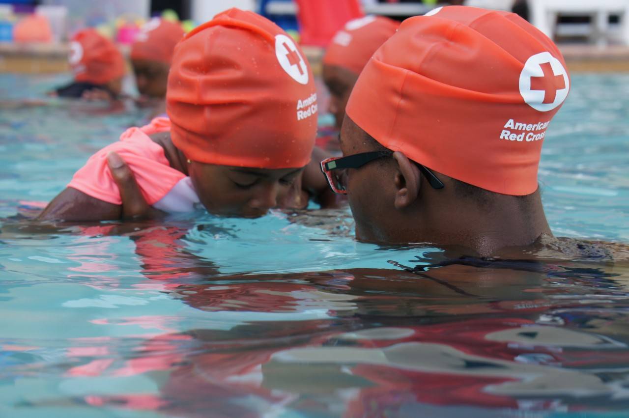 July 16, 2019. Opa Locka, Florida. The Centennial Campaign celebrates more than 100 years of American Red Cross swimming safety education. Cities selected for the campaign have high numbers of fatal drownings or overall drowning rates, most higher than the national average. Working with local aquatics training providers, we’ve taught thousands of people in 50 selected cities across 19 states how to swim and be safe in and around the water. 

In this photo, an adult works with a child learning how to breathe properly in the water.
Photo by Eliza Shaw/American Red Cross