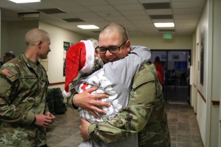 Red Cross volunteer Petra Yahn hugs a soldier as Fort Sill’s holiday block leave begins on Dec. 15. Yahn is “like a family member” to the brigade.