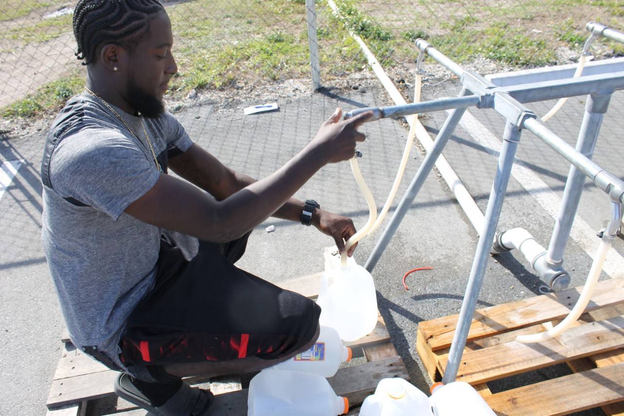 March 11, 2020. Freeport, Grand Bahama, Bahamas. In Freeport, Grand Bahama the water is still not safe to drink following Hurricane Dorian so hundreds of people stop by the free water distribution sites set up around the island to fill up on drinking water. The American Red Cross is funding these sites set up and managed by a partner, Mercy Corps. Mercy Corps employee Julian Cooper helps fill jugs and other containers for people in the parking lot of the local Salvation Army. Photo by Holly Baker/American Red Cross