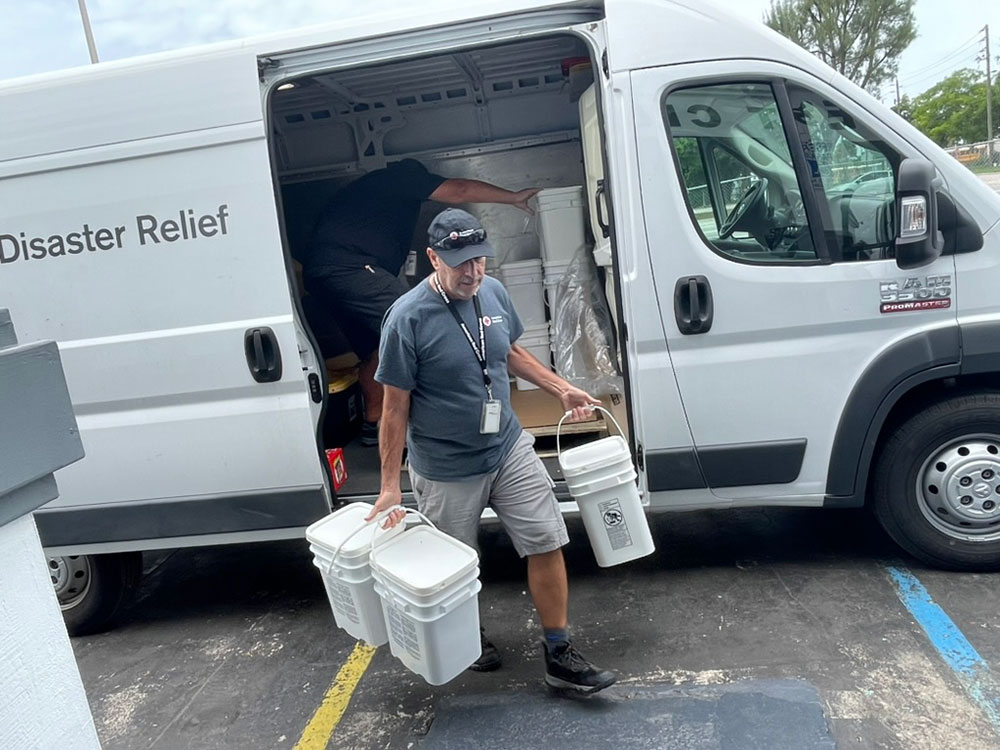 Volunteer carrying buckets that were unloaded from a Red Cross Disaster Relief vehicle.