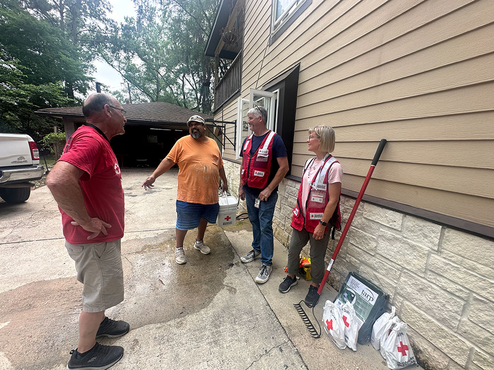 Red Cross volunteers speaking with resident outside house