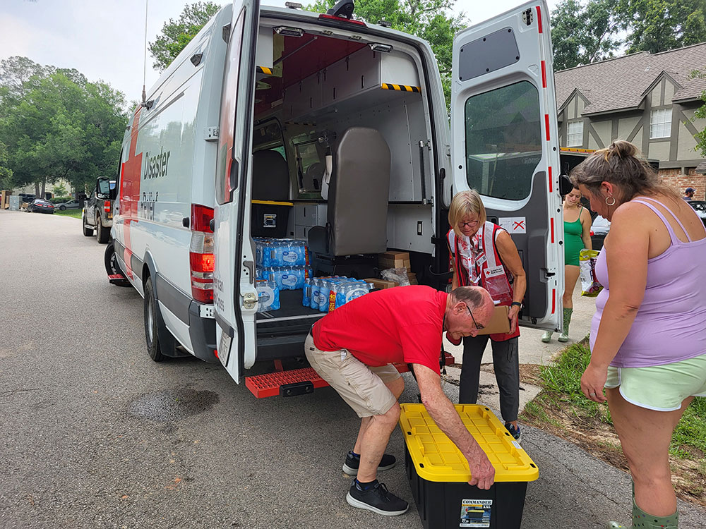 Paul Henke unloads a tote box while Suzanne Pehl unloads a box from Red Cross vehicle