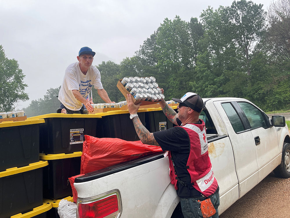 Red Cross volunteers loading truck bed with containers and drinks