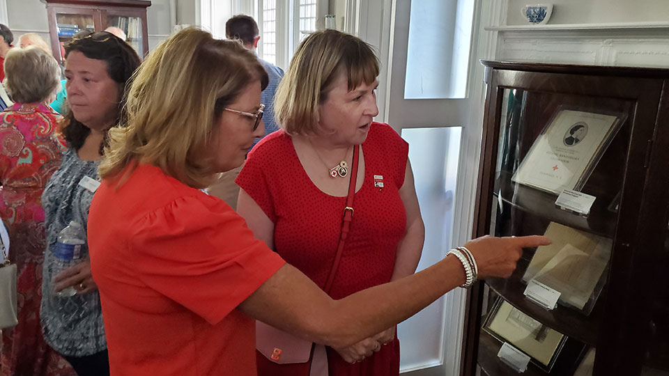 Guests inside the Clara Barton Chapter 1 building looking at pictures behind glass enclosure.