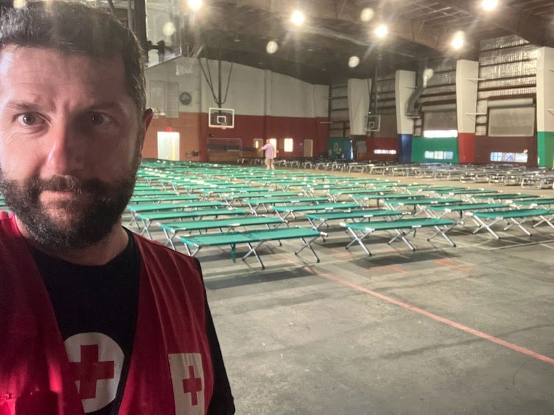 Red Cross volunteer in gym with cots