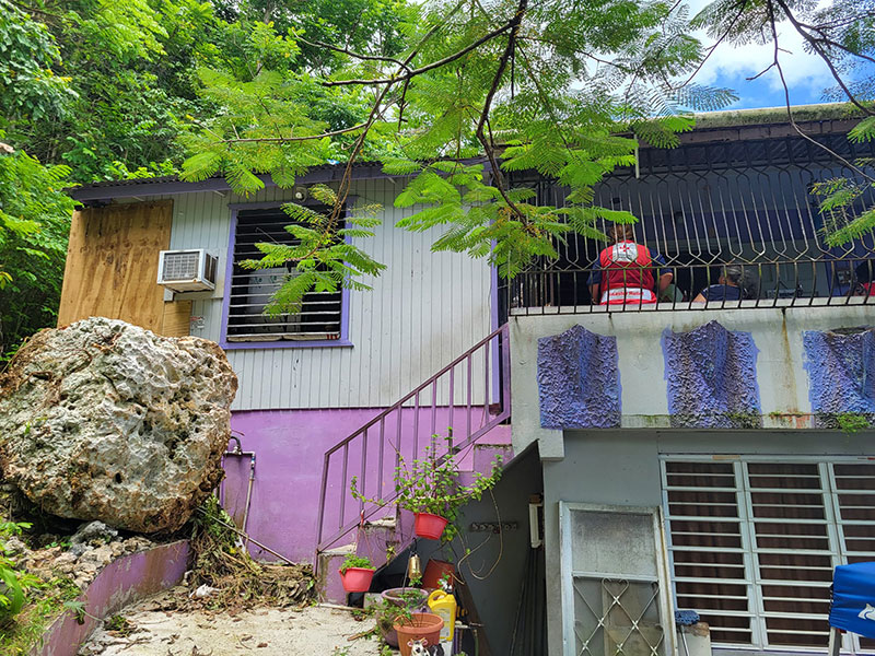 House with Red Cross volunteer and residents sitting on balcony.