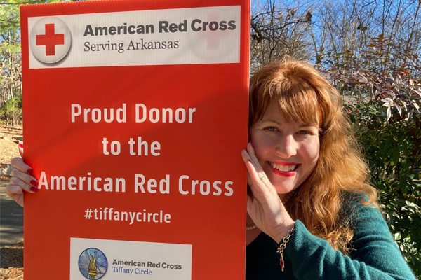 Andrea Davis holding up a red Proud Donor to the American Red Cross sign