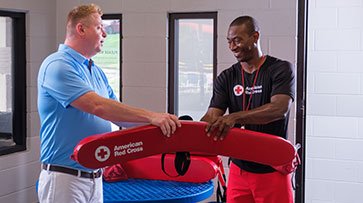 Certified Red Cross lifeguard receiving red rescue tube.