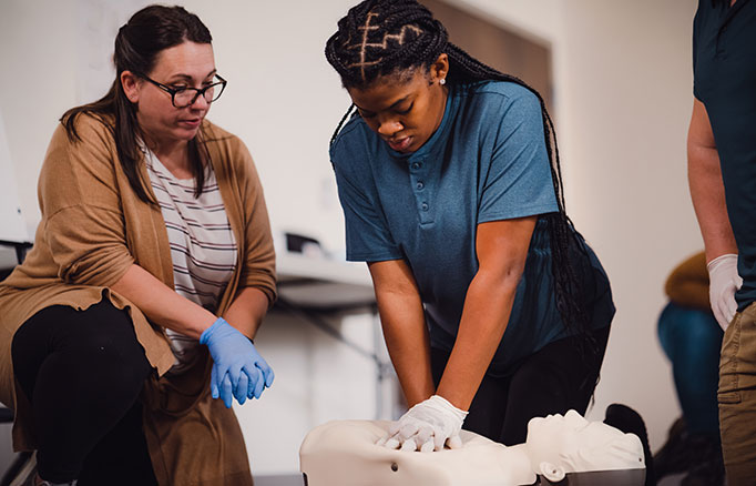 Individuals in a CPR training class practicing chest compressions on CPR manikins.