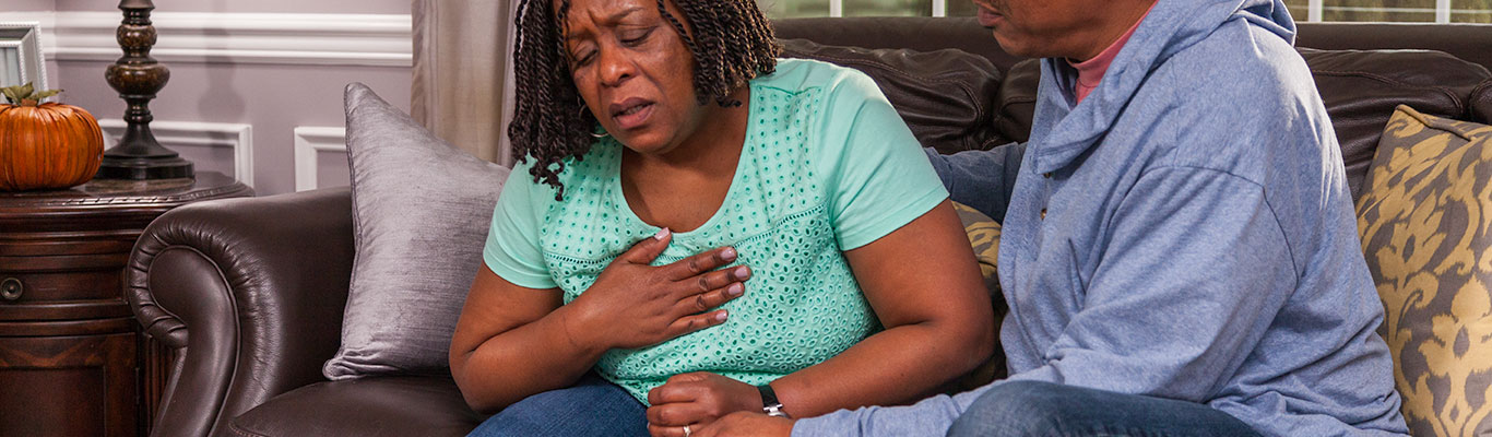 Woman experiencing a heart attack or cardiac arrest, clutching her chest in pain.