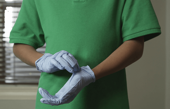 Individual practices safe removal of medical gloves.