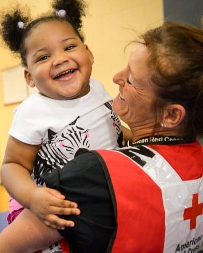A Red Cross volunteer holding a child.