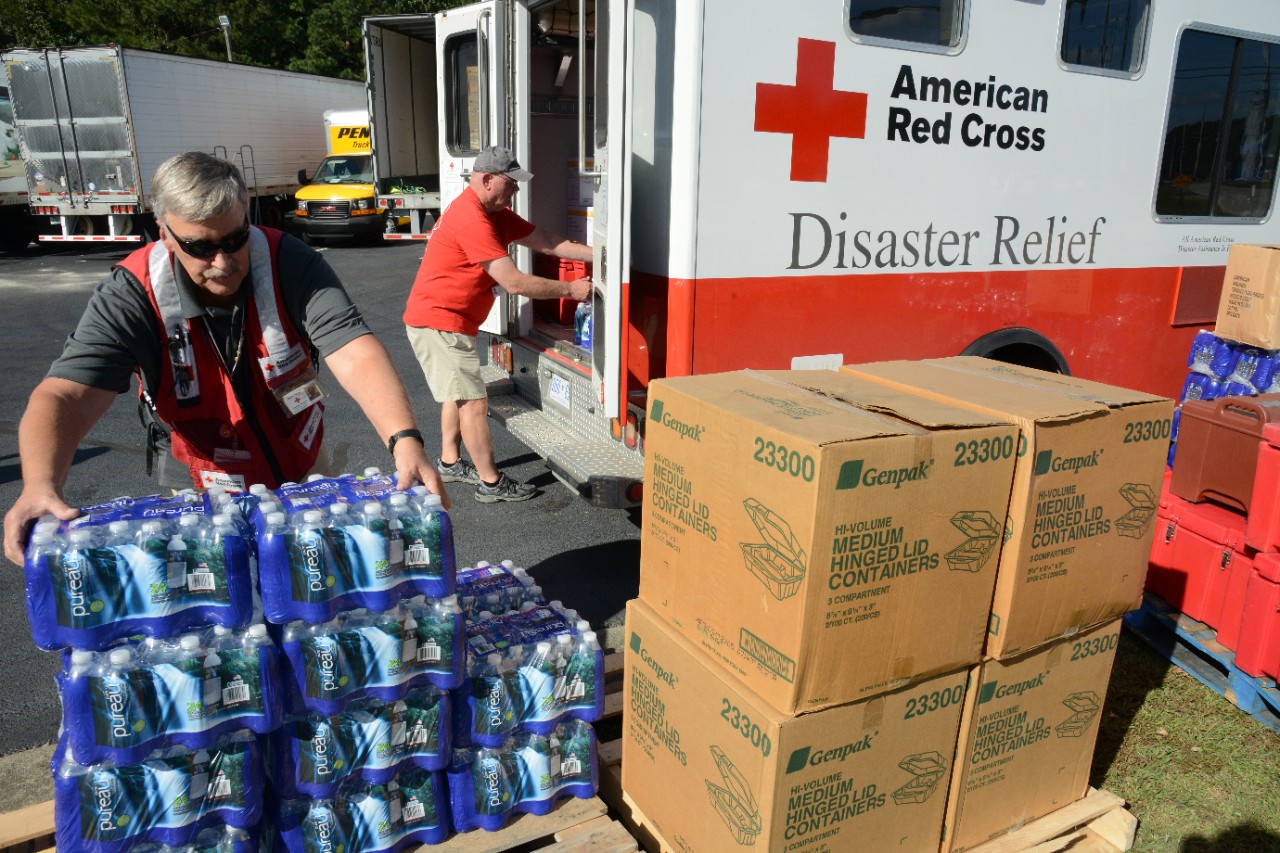 Two American Red Cross volunteers loading packages of water into the back of an American Red Cross Disaster Relief vehicle.