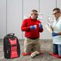 Red Cross First Aid Instructor showing a student how to use a Tourniquet Arm Trainer, and a Red Cross Instructor bag.